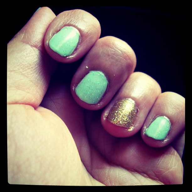 green nail polish and a golden glittering one on the ring finger only